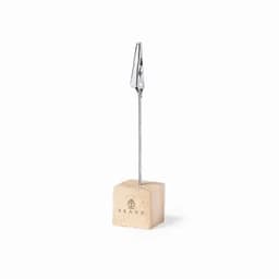 A cork clip holder with a metal clip attached to a thin wire, resting on a square cork base.