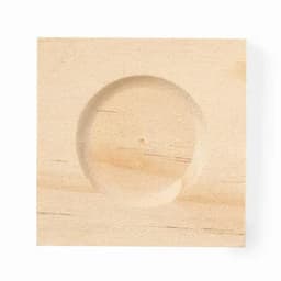 A wooden block with a round recessed area in the centre, showcasing a light natural wood finish.