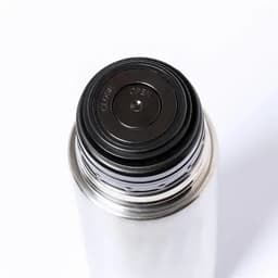 A drink bottle with a stainless steel finish and a black screw cap featuring a rubber seal.