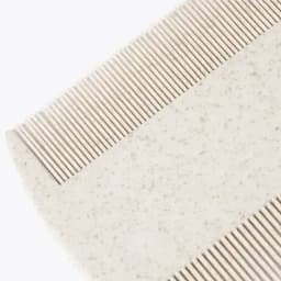 A grooming comb in light beige with fine and wide teeth, featuring a smooth edge. It has a subtle speckled texture.