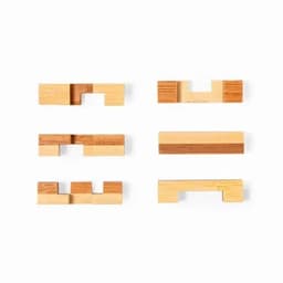 A collection of wooden puzzle pieces in various shapes and shades of light and dark wood, arranged in two rows.