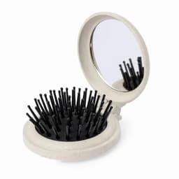 A compact mirror with a brush featuring black bristles, set in a light grey case.