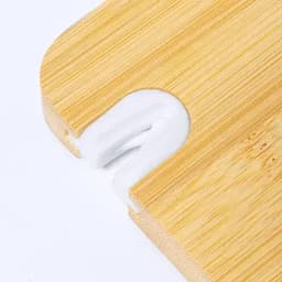 A bamboo cutting board with a white silicone grip. The board has rounded edges and a small cut-out for handling.