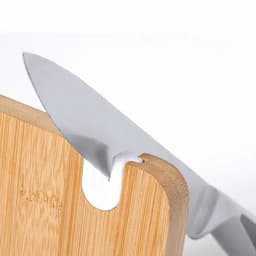 A kitchen knife with a silver blade rests against a wooden chopping board, showcasing a sleek design.