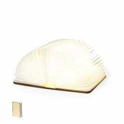 A book-shaped lamp with a flexible, white, fan-like design, alongside a small, black notebook.