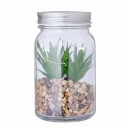 A glass jar containing artificial green plants and pebbles, featuring a metal lid.