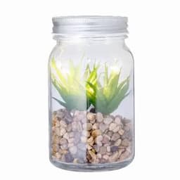 A glass jar containing decorative pebbles and artificial green plants, with light enhancing its appearance.