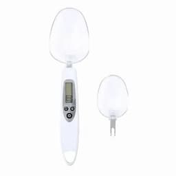 A digital kitchen scale with a clear scoop and detachable measuring spoon. The product is white with a digital display.