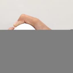 A drink bottle in a hand, featuring a smooth white surface and a sleek, rounded design.
