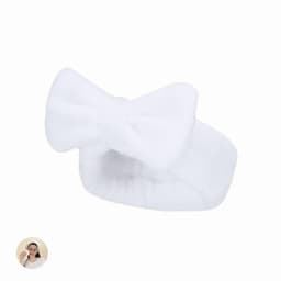 A white, fluffy headband with a bow design is displayed on a plain background.