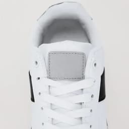 A sneaker with a white upper and black detailing, featuring shoelaces and a grey patch at the front.