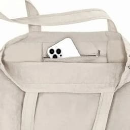 A light grey tote bag featuring a zippered pocket holding a smartphone inside. The bag has two sturdy handles.