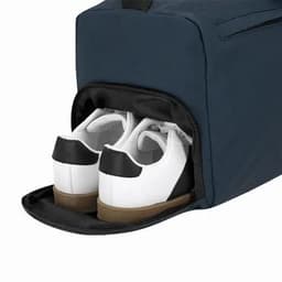 A shoe compartment opens to reveal white sneakers with black detailing, inside a navy bag.