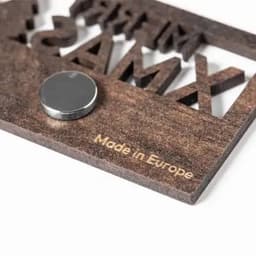 A wooden promotional item featuring raised letters and a metallic disc, with text indicating it's made in Europe.
