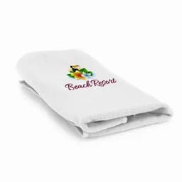 A folded white towel with a floral design and a logo featuring the text "Beach Resort."