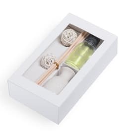 A gift box containing a small bottle of yellow liquid, wooden sticks, and decorative white balls.