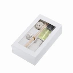 A boxed product containing a small bottle of liquid, wooden sticks, and two decorative white spheres.