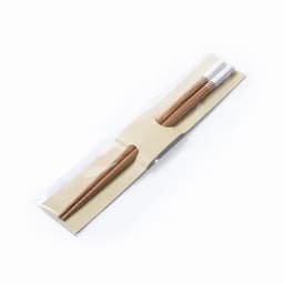 A pair of wooden chopsticks in a clear plastic packaging with a beige backing.
