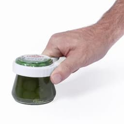 A jar of green olives with a white lid being held by a hand. The jar has a logo on the lid.
