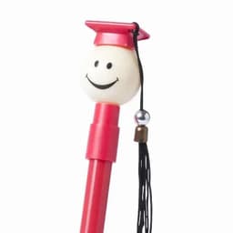 A red pen topped with a smiley face and a mini graduation cap, featuring a black tassel and a decorative bead.