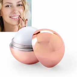 A rose gold spherical lip balm container, slightly open to reveal the product inside, with a smiling woman in the background.