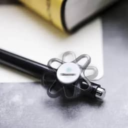 A black pen with a floral-shaped grip resting on a notebook and a book's edge in the background.