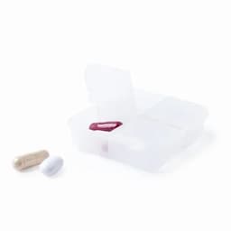 A pill organiser with four compartments, featuring three capsules in various colours: white, beige, and red.