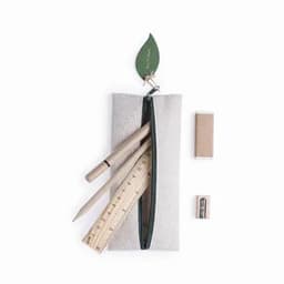 A pencil case in light grey fabric, containing wooden pencils, a ruler, an eraser, and a sharpener, topped with a leaf design.