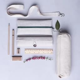 A stationery set featuring a light-coloured pouch, pencil case, wooden pencils, a ruler, a sharpener, and a plant.