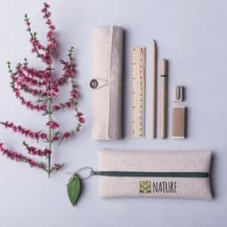 A stationery set featuring a cream pencil case, ruler, pencil, sharpener, and eraser, arranged with pink flowers.