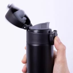 A drink bottle in sleek black with a grey lid, featuring a flip-top design and a secure clasp.