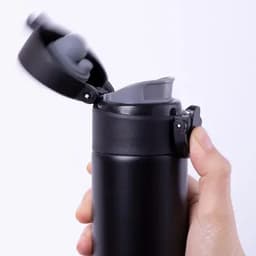 A drink bottle in matte black with a grey lid, featuring a spout and a secure locking mechanism.