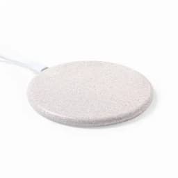 A round, white charging pad with a textured surface and a connected cord.