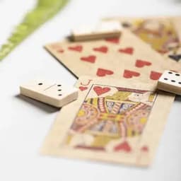 A set of playing cards featuring hearts and a king, alongside two dominoes, all on a light background.