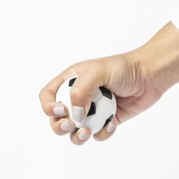 A hand squeezing a white stress ball shaped like a soccer ball, featuring black pentagonal patches.