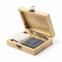 A bamboo box containing six grey whisky stones, a pair of tongs, and a grey cloth. The box has a clasp closure.