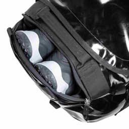 A black barrel roller featuring a compartment for shoes, with a glossy finish and zippers visible.