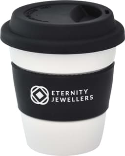 A reusable ceramic mug in white with a black silicone lid and sleeve, featuring a logo.