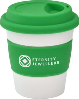 A reusable coffee cup featuring a green silicone lid and sleeve with a white body. The cup has a logo.