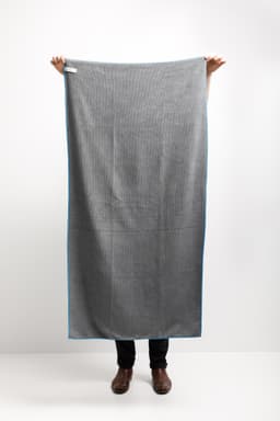 A grey car drying towel with blue trim, measuring 150x75cm, held by a person against a plain background.