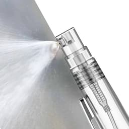 A clear sanitiser spray pen with a fine mist nozzle, positioned against a reflective surface.