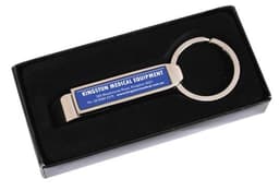 A drink bottle opener in silver sits within a black gift box, featuring a branding logo on its side.