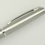 A sleek silver metal pen with a clip and a smooth body, featuring a logo on the side.