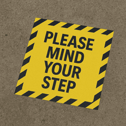 A yellow floor decal sticker with black striped edges and text instructing to "MIND YOUR STEP."