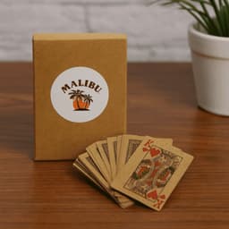 A deck of eco-friendly playing cards in brown packaging with a logo, showcasing several cards with colourful designs.