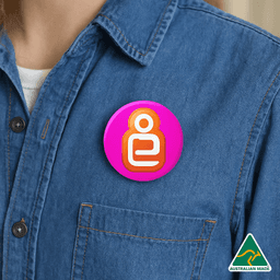 A 32mm button badge featuring vibrant pink and orange colours, worn on a denim shirt with a logo in the corner.