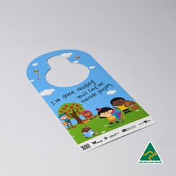 A door hanger featuring a colourful design with children playing outside, set against a blue background and greenery.