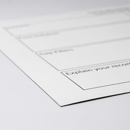 A white magnetic whiteboard with black outline sections for notes, featuring a logo in the corner.