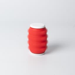 A red drink bottle with a white lid and a textured design, displaying motion blur effects.
