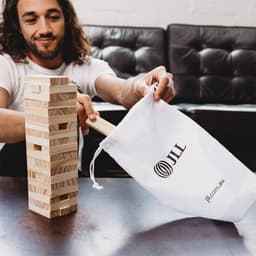 A stacking puzzle set in natural wood colour, accompanied by a white pouch with a logo.